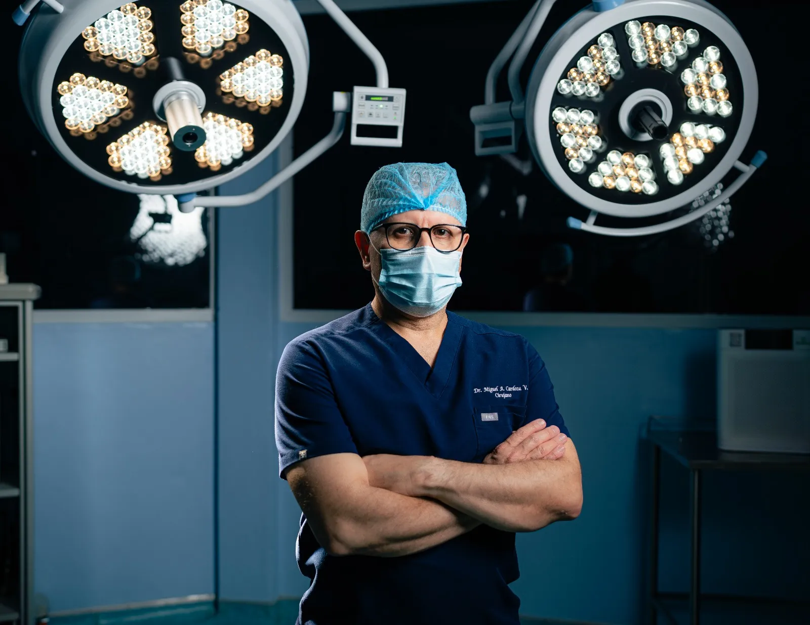 Dr. Miguel Cardoza en el quirófano, con la lámpara quirúrgica encendida, brazos cruzados
